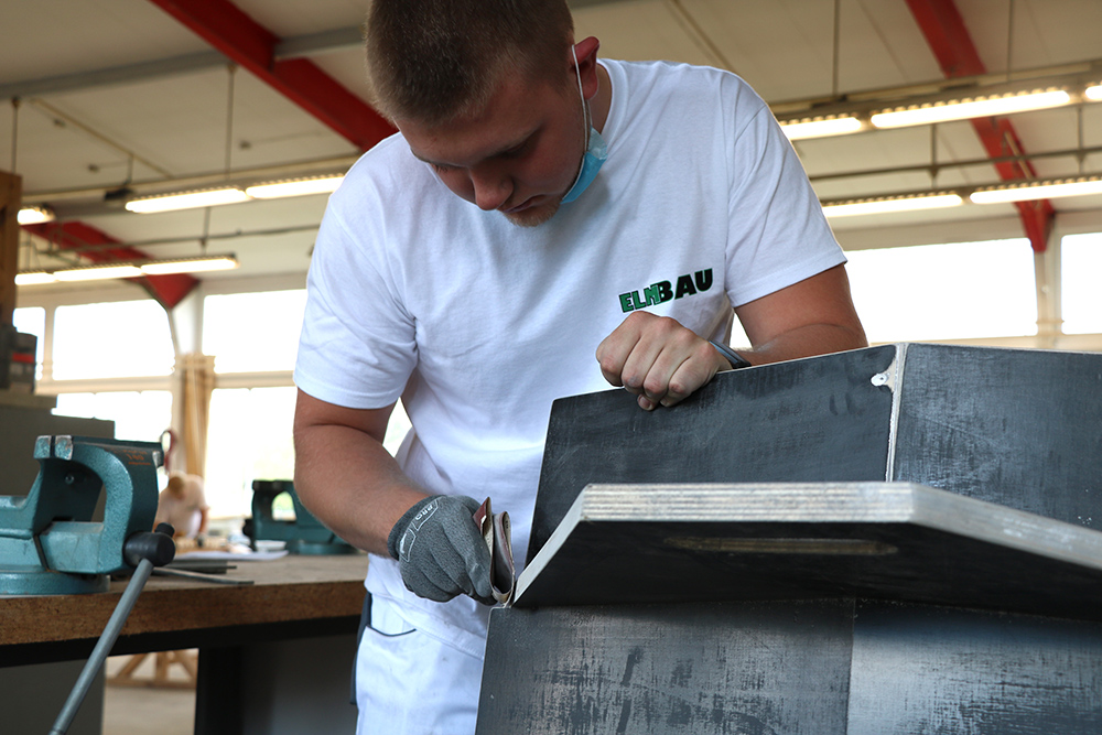 ElmBau - Ausbildung zum Maler, Azubis verdichten eine Fassade und streichen sie glatt im Ausbildungszentrum